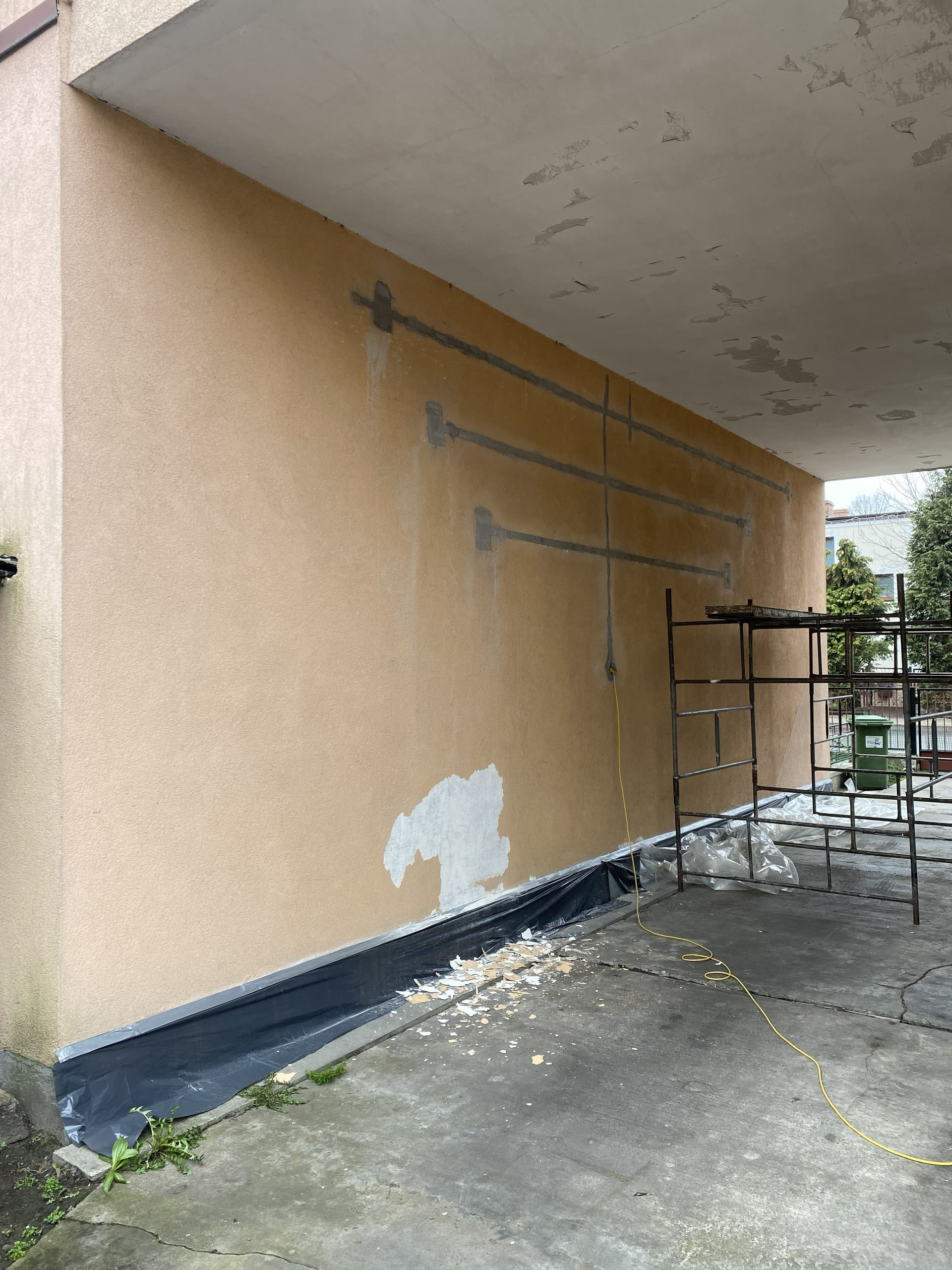 Przejazd w bloku przed renowacją - odpadający tynk, ślady starych instalacji, scaffolding - realizacja STmaster Goleniów