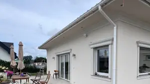 Narożnik parterowego domu z jasnym tynkiem i białą podbitką pod okapem - miejsca, w których dzięcioł w styropianie kuje najczęściej